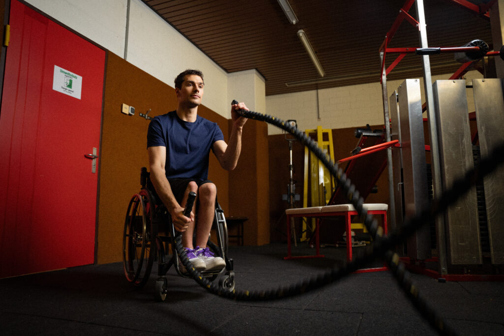 A paralympic athlete in a wheelchair using battle ropes in a gym, filmed with high-quality video equipment, ideal for adding dynamic stock footage and sound effects to video projects